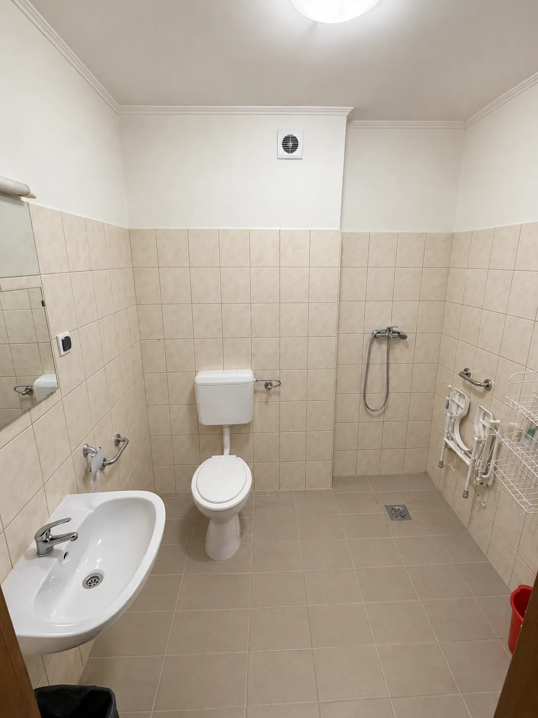 Akadálymentesített fürdőszoba mosdóval, WC-vel, küszöb nélküli zuhanyzóval és kapaszkodókkal
